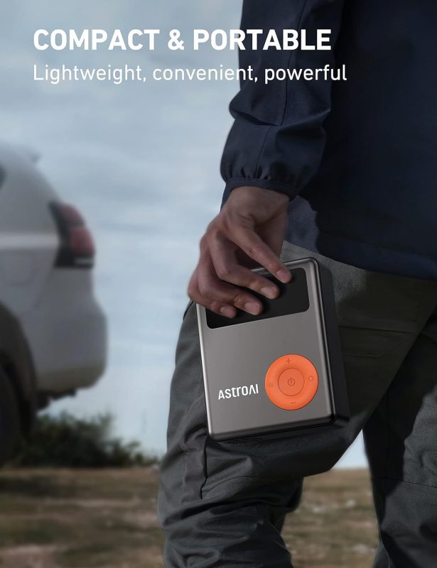 Person holding an ASTROAI portable device with orange control panel in an outdoor setting near a vehicle