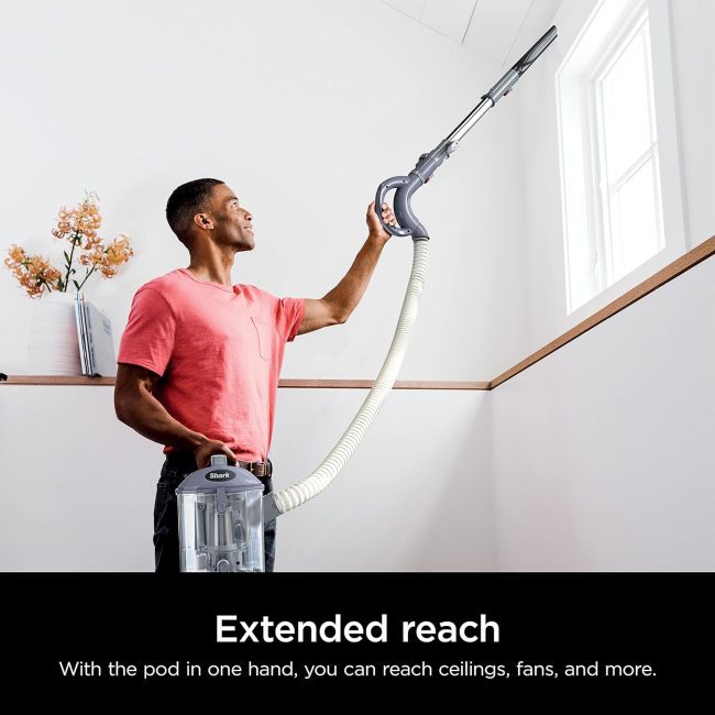 Person using a vacuum cleaner with extended reach to clean a high window