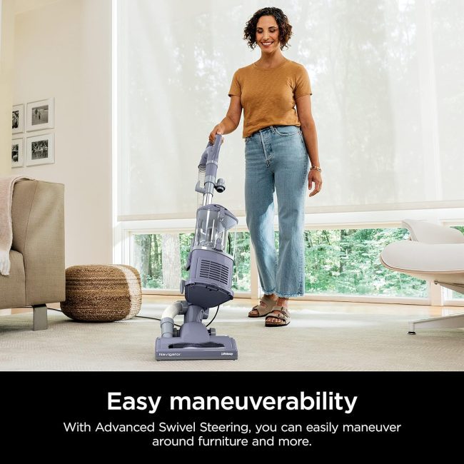 Person using a Navigator Lift-Away vacuum cleaner in a well-lit living room, showcasing easy maneuverability on the carpet