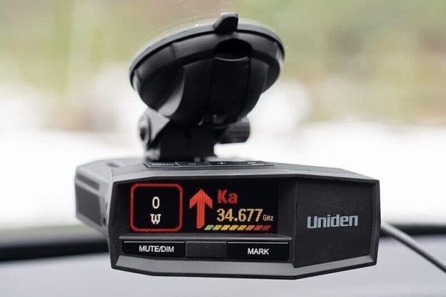 Uniden radar detector mounted on vehicle windshield displaying detection of Ka-band radar signal at 34.677 GHz.