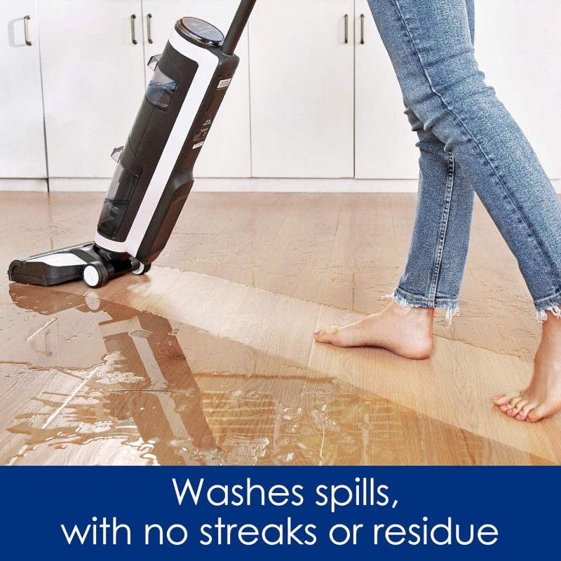 Person using a floor cleaning device to clean a spill on a wooden floor