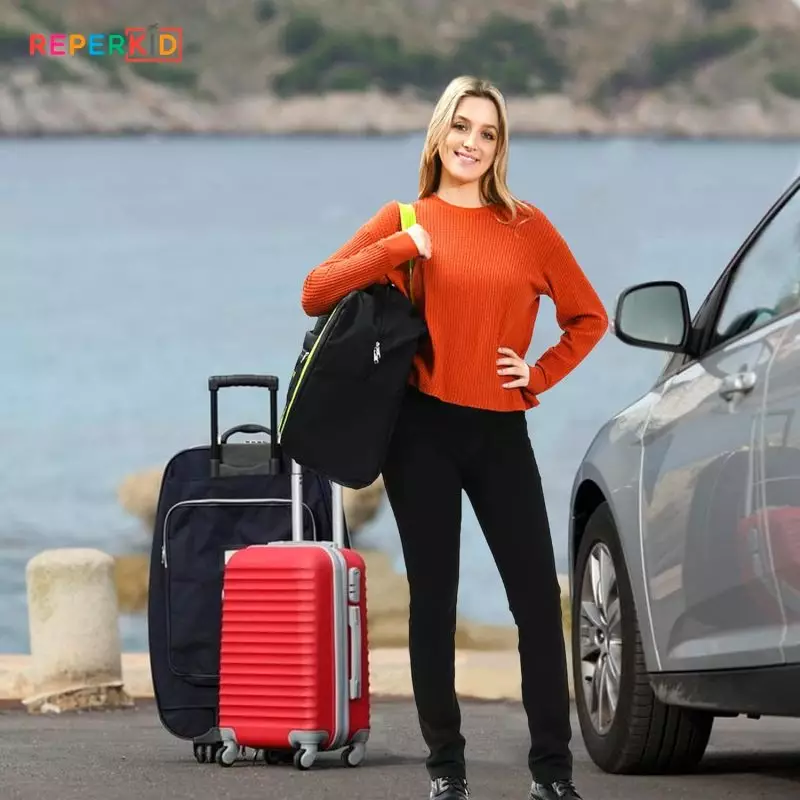 Young Woman Preparing for Road Trip with Booster Seat Travel Bag Woman in orange standing by car with booster car seat travel bag near a scenic lake