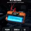 Automotive jump starter connected to a car battery, displaying full charge on LED