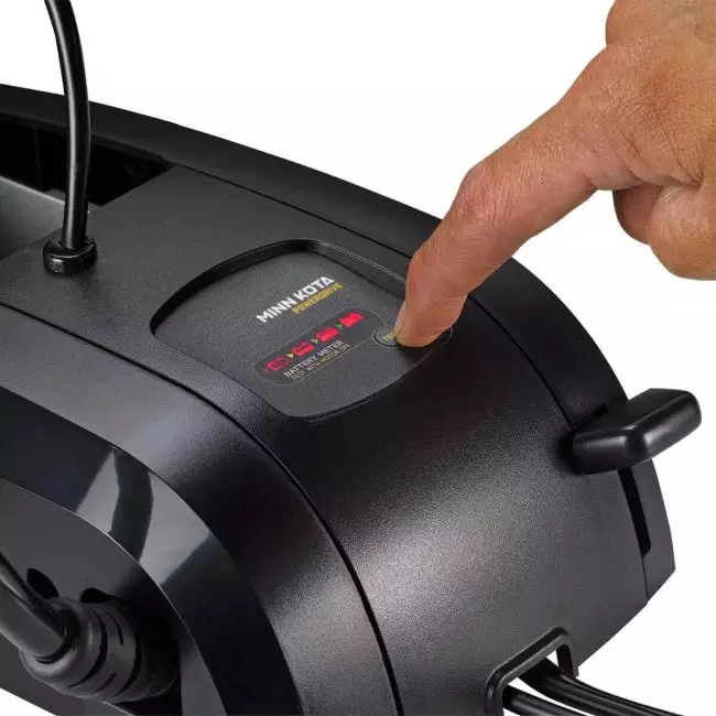 Close-up of a hand pressing the activation button on a Minn Kota PowerDrive control panel