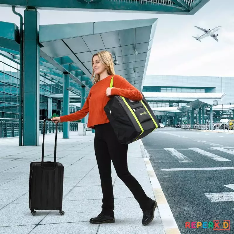 Woman walking outside airport terminal with a booster car seat travel bag and suitcase
