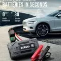 Zukaka portable car jump starter with red and black cables next to a white car,   highlighting its capability to start 99% dead batteries in seconds.