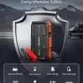 Portable vehicle jump starter with cables attached,   set against a mountainous backdrop,   highlighting safety features like reverse polarity and short circuit protection