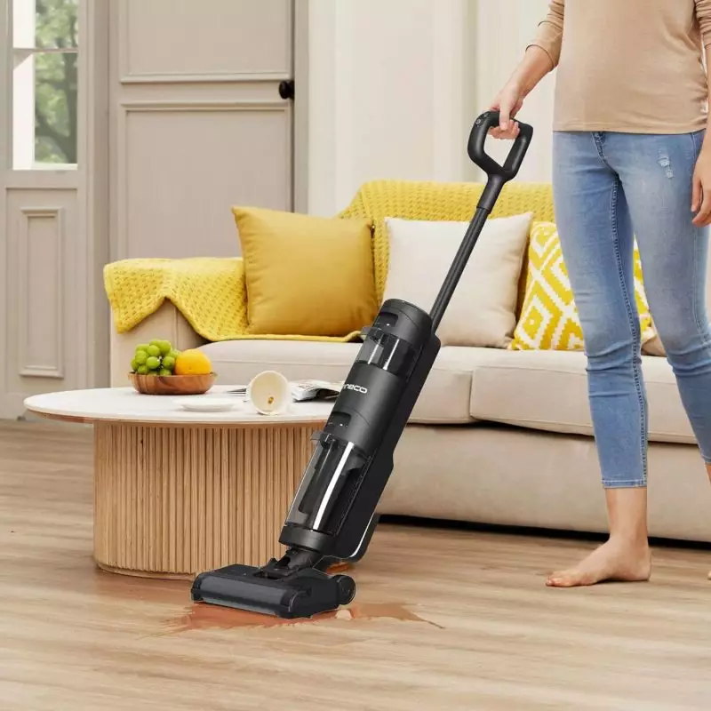 Efficient Cleanup with Modern Vacuum Cleaner on Wooden Floor Person using a vacuum cleaner on a wooden floor with a spill near a coffee table and beige sofa