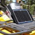 Yellow Outlander 650 MAX ATV with a solar panel on its back,   used for charging devices or batteries.