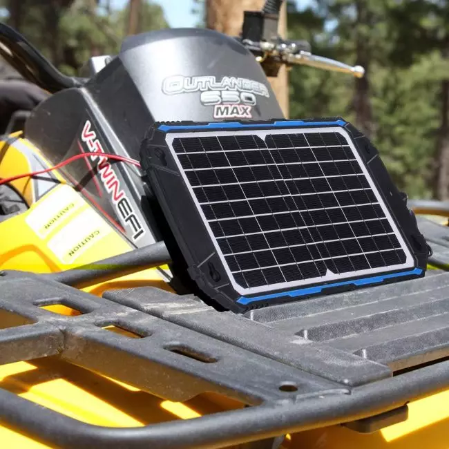 Yellow Outlander 650 MAX ATV with a solar panel on its back, used for charging devices or batteries.